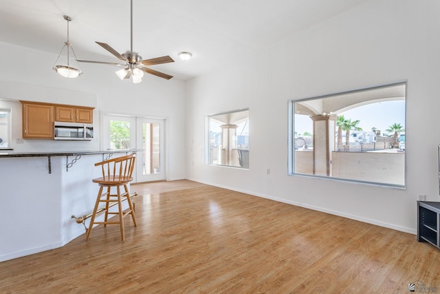 unfurnished living room featuring ceiling fan, baseboards, and light wood-style floors