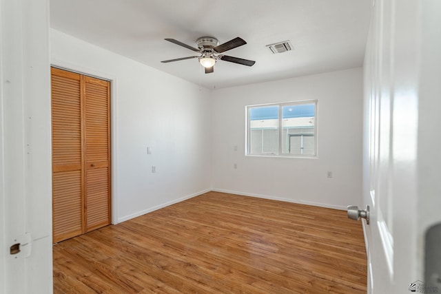 unfurnished bedroom featuring baseboards, a closet, light wood finished floors, and visible vents