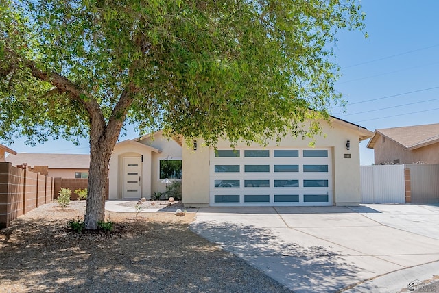 view of front of property with stucco siding, a garage, fence, and driveway