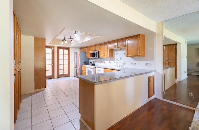 800 E Country Club Dr Unit 26, Yuma, AZ 85365 - kitchen featuring appliances with stainless steel finishes, a sink, a tray ceiling, light wood-style floors, and a peninsula