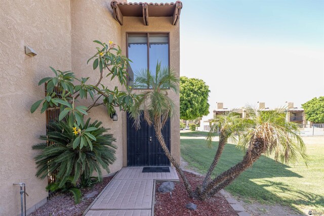 800 E Country Club Dr Unit 26, Yuma, AZ 85365 - view of exterior entry featuring stucco siding and a lawn