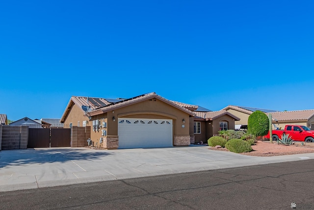 11594 E 27th Pl, Yuma, AZ 85367 - ranch-style house with stucco siding, an attached garage, a gate, a tile roof, and roof mounted solar panels