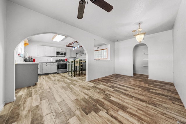 2621 S Walnut Ave, Yuma, AZ 85364 - kitchen with stainless steel appliances, a ceiling fan, light wood-type flooring, arched walkways, and light countertops