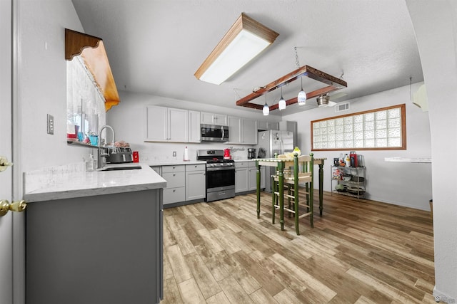 2621 S Walnut Ave, Yuma, AZ 85364 - kitchen featuring appliances with stainless steel finishes, gray cabinetry, light wood finished floors, and light stone countertops