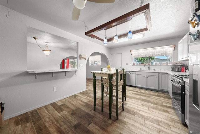 2621 S Walnut Ave, Yuma, AZ 85364 - kitchen featuring stainless steel appliances, arched walkways, light countertops, light wood finished floors, and a ceiling fan