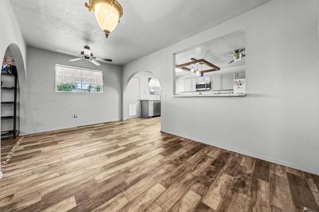 2621 S Walnut Ave, Yuma, AZ 85364 - unfurnished living room featuring ceiling fan, arched walkways, and wood finished floors