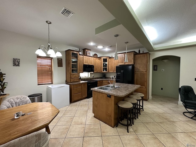 14411 E 50th Dr, Yuma, AZ 85367 - kitchen featuring black appliances, arched walkways, glass insert cabinets, light tile patterned floors, and vaulted ceiling