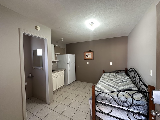 14411 E 50th Dr, Yuma, AZ 85367 - bedroom with freestanding refrigerator, light tile patterned floors, and a textured ceiling