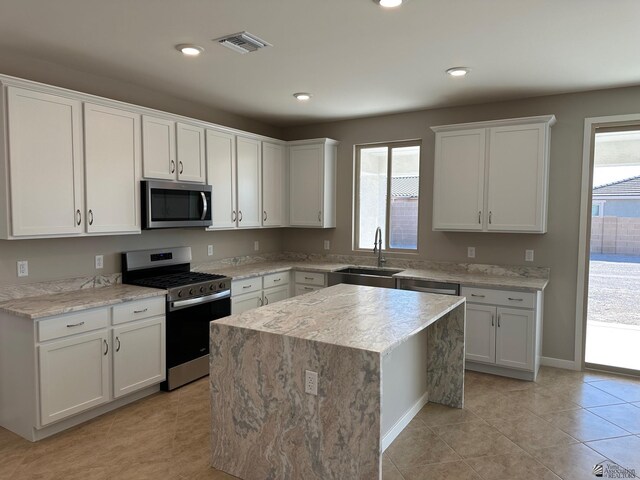 14691 E 42nd St, Yuma, AZ 85367 - kitchen with stainless steel appliances, white cabinetry, a kitchen island, light stone countertops, and light tile patterned floors