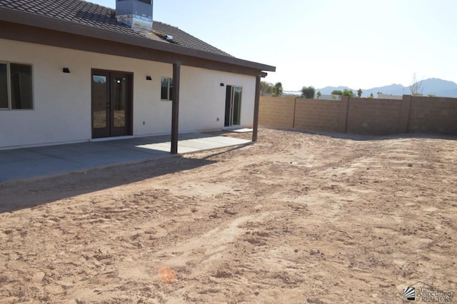 13113 E 54th St Lot 37, Yuma, AZ 85367 - back of house with a patio area, a mountain view, stucco siding, a chimney, and french doors