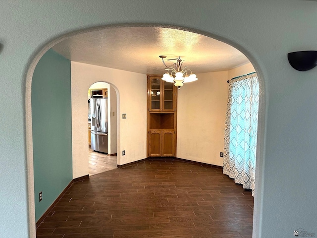 1319 W 18th Pl, Yuma, AZ 85364 - spare room featuring dark wood finished floors, arched walkways, a chandelier, and baseboards