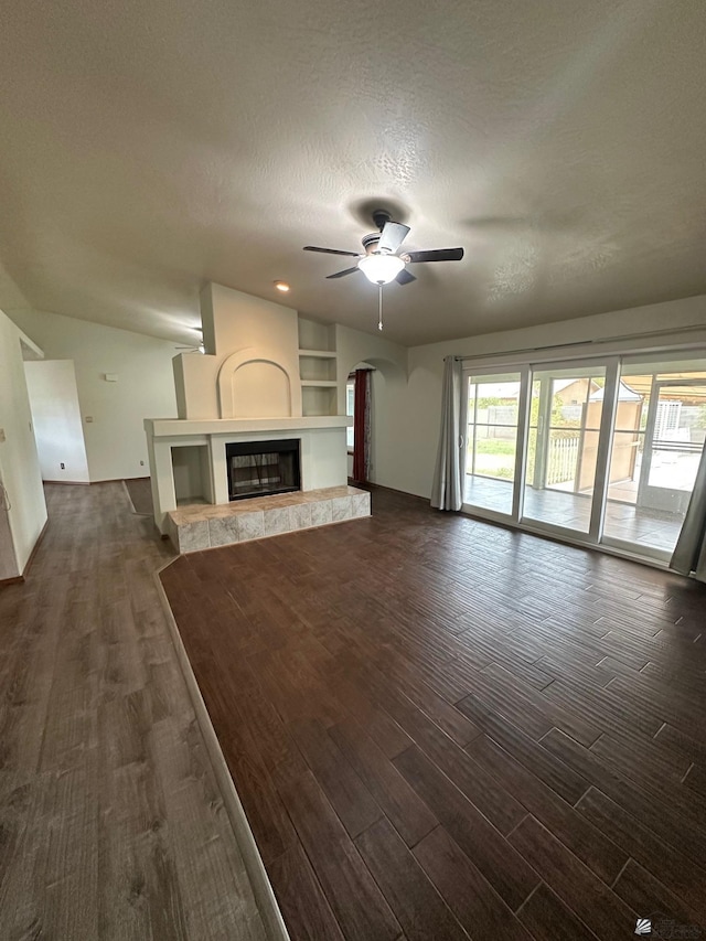 1319 W 18th Pl, Yuma, AZ 85364 - unfurnished living room with dark wood-type flooring, a ceiling fan, a tiled fireplace, a textured ceiling, and arched walkways