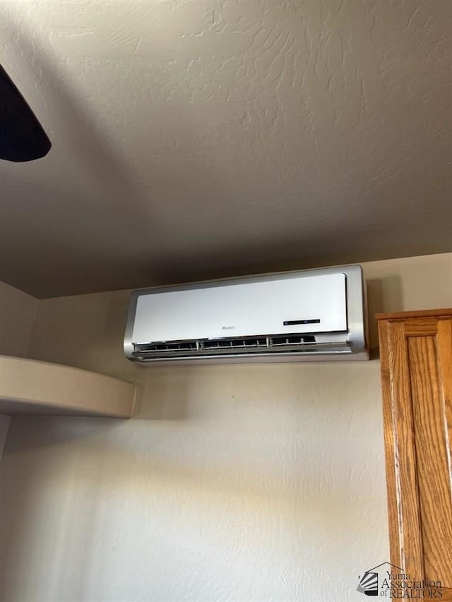 interior details featuring a wall mounted AC and a textured ceiling