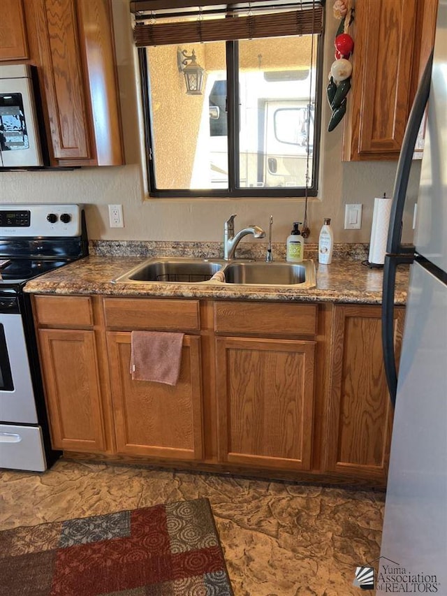 kitchen featuring white range with electric stovetop, stainless steel fridge, and sink