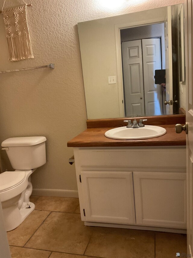 bathroom featuring toilet, baseboards, tile patterned flooring, and vanity