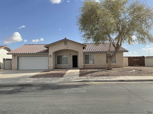 mediterranean / spanish house featuring a tiled roof, an attached garage, and stucco siding