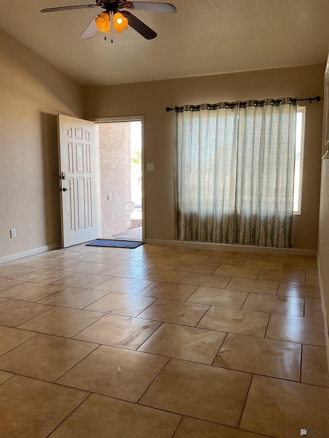 spare room with baseboards and a ceiling fan