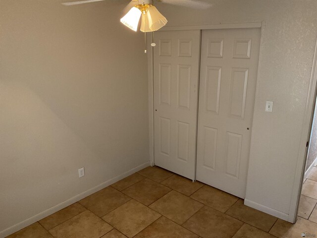 unfurnished bedroom featuring baseboards, ceiling fan, light tile patterned floors, and a closet