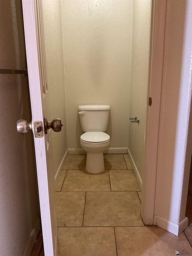 bathroom with baseboards, tile patterned floors, and toilet