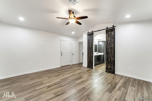 12616 E 49th Dr, Yuma, AZ 85367 - empty room with a ceiling fan, visible vents, light wood-type flooring, a barn door, and baseboards