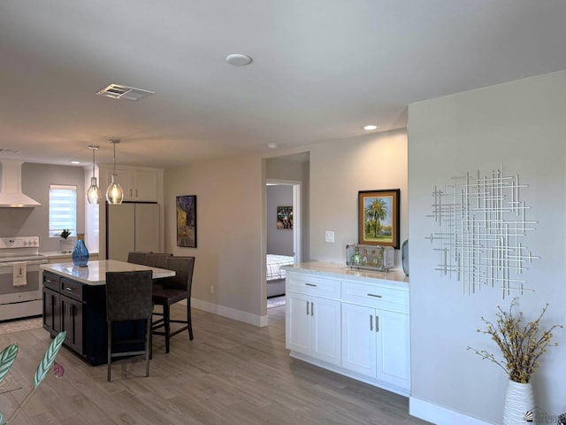 kitchen featuring white electric range oven, white cabinets, exhaust hood, and visible vents