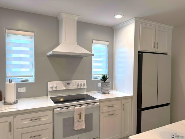 kitchen with white cabinets, freestanding refrigerator, white electric stove, and wall chimney exhaust hood