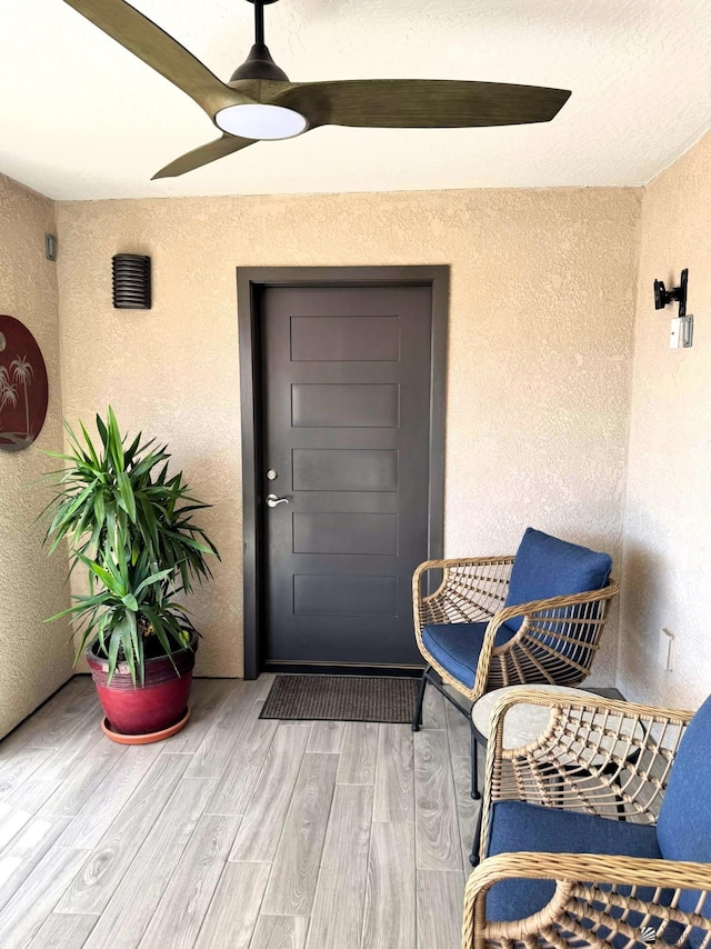 view of exterior entry with ceiling fan and stucco siding