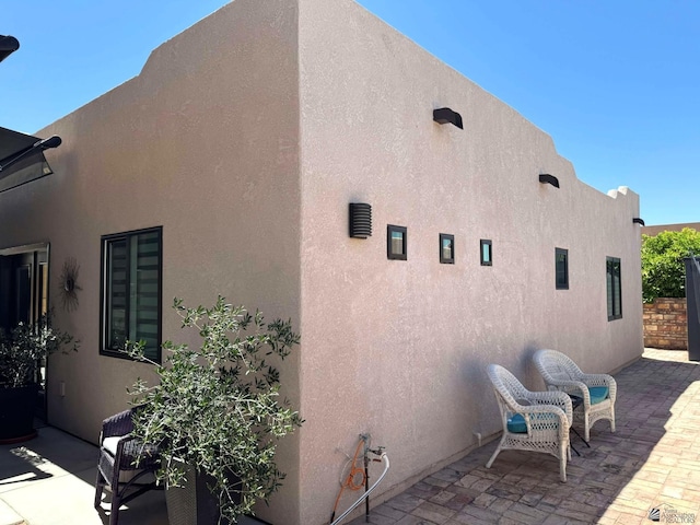 view of side of home featuring stucco siding and a patio area
