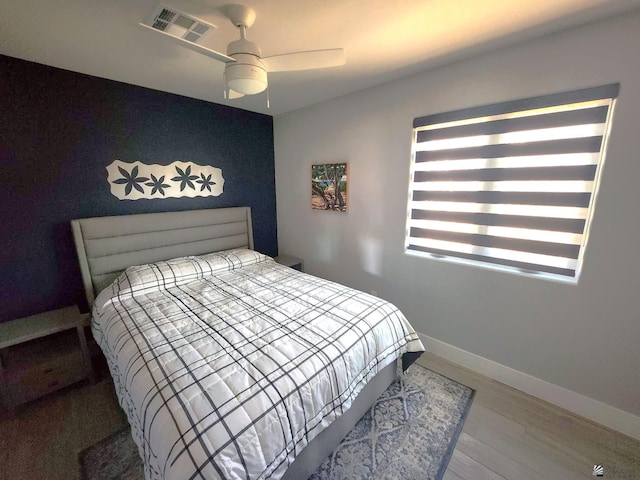bedroom with a ceiling fan, baseboards, visible vents, and wood finished floors