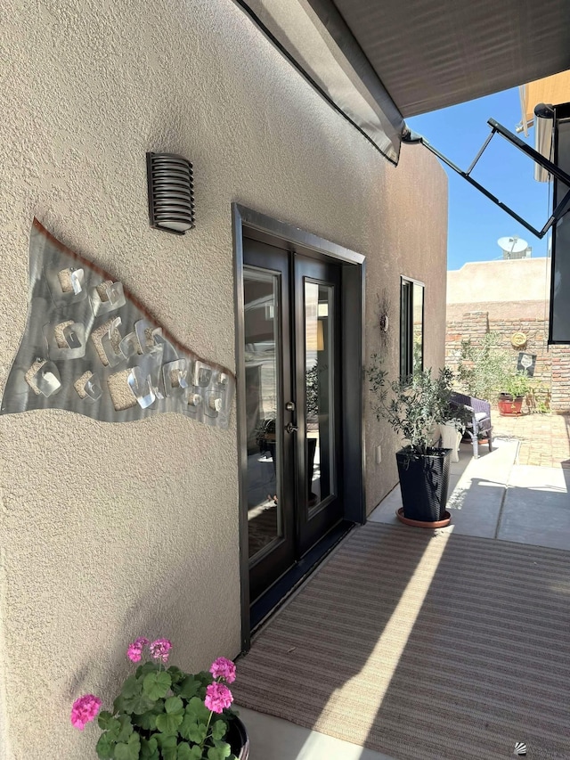 view of exterior entry with a patio, stucco siding, and french doors