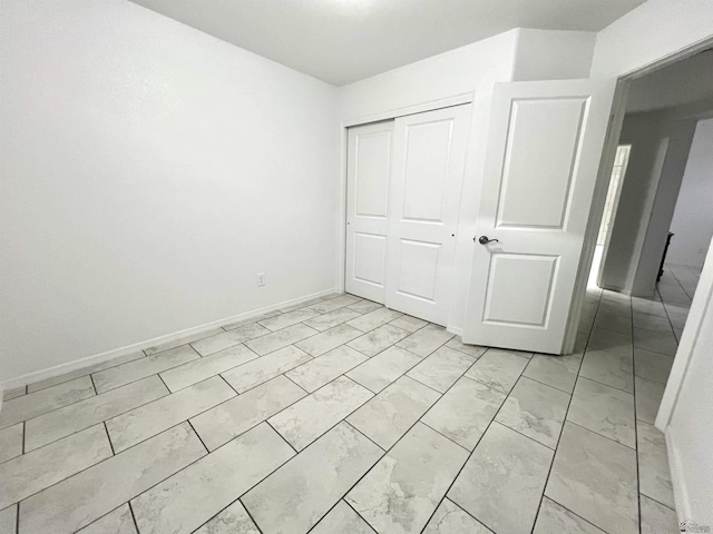 8756 E 41st St, Yuma, AZ 85365 - unfurnished bedroom with light marble finish floors, a closet, and baseboards