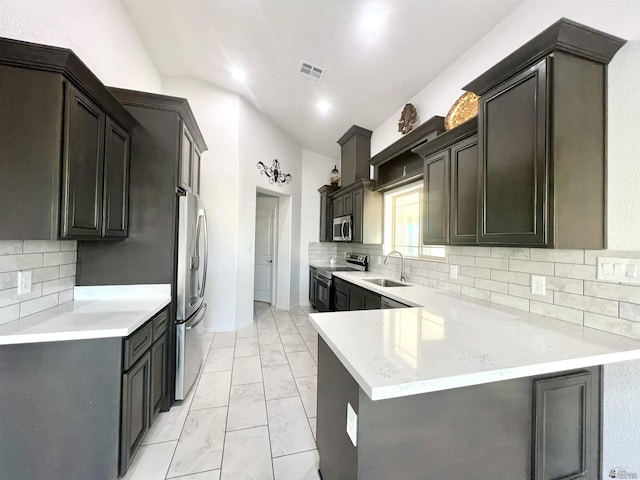 8756 E 41st St, Yuma, AZ 85365 - kitchen with appliances with stainless steel finishes, a sink, vaulted ceiling, a peninsula, and tasteful backsplash