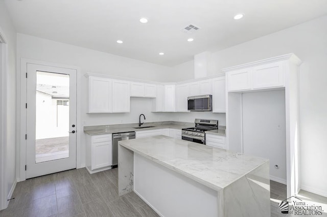 kitchen with a sink, a kitchen island, stainless steel appliances, and white cabinets