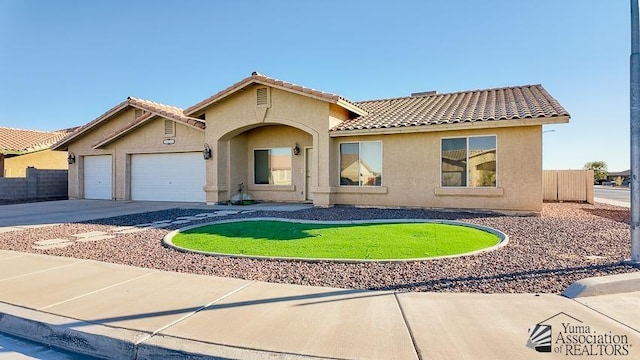 mediterranean / spanish-style home with fence, a tiled roof, stucco siding, a garage, and driveway