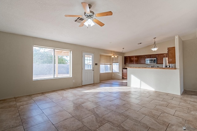 unfurnished living room featuring vaulted ceiling and ceiling fan