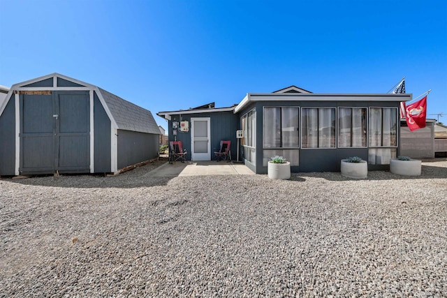 14419 E Fortuna Palms Pl, Yuma, AZ 85367 - rear view of house with a sunroom, an outdoor structure, a storage shed, and a patio