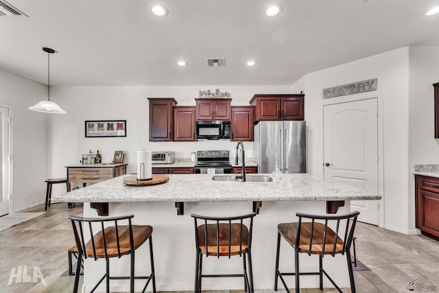 kitchen featuring a kitchen bar, sink, high end refrigerator, range with electric stovetop, and a kitchen island with sink