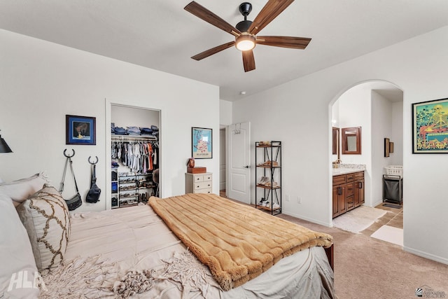 carpeted bedroom featuring ceiling fan, a walk in closet, ensuite bath, and a closet