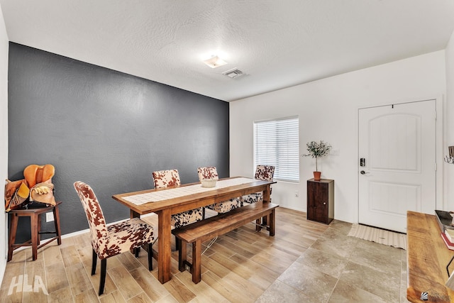 dining area featuring a textured ceiling and light wood-type flooring