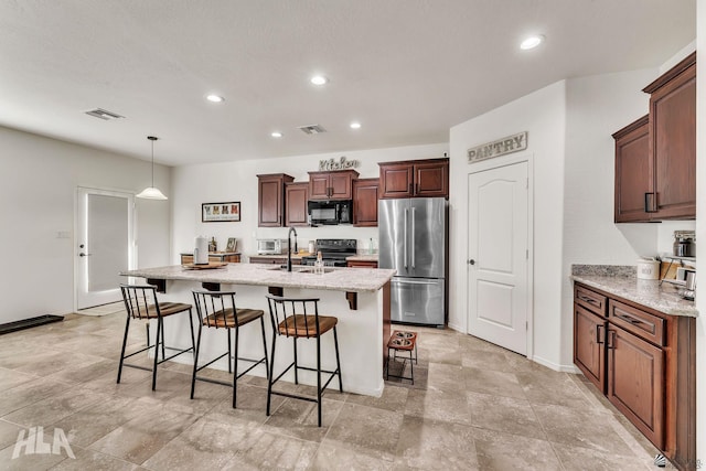 kitchen featuring pendant lighting, a breakfast bar, light stone countertops, black appliances, and a center island with sink