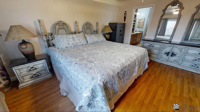 bedroom featuring ensuite bath and wood finished floors