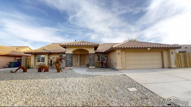 mediterranean / spanish home featuring a tiled roof, driveway, fence, an attached garage, and stucco siding
