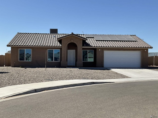 ranch-style house with solar panels, a tile roof, a garage, concrete driveway, and stucco siding