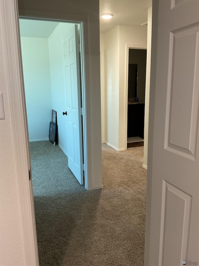 corridor with baseboards and carpet