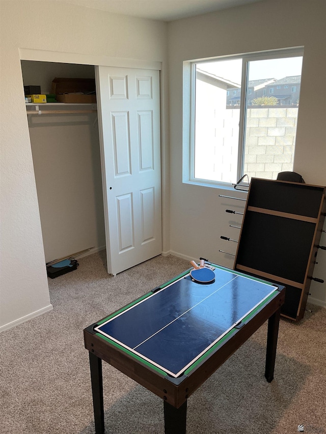 rec room featuring light colored carpet and baseboards