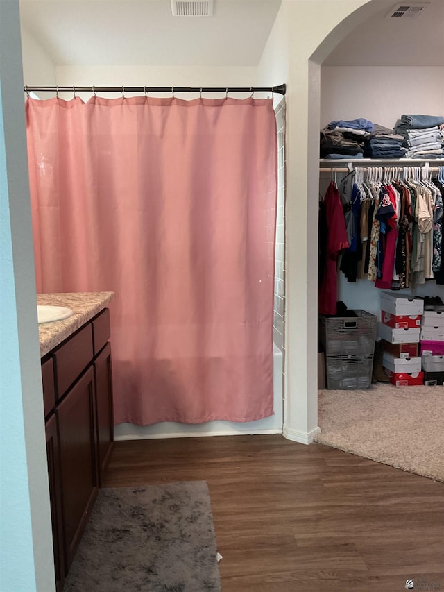 bathroom featuring visible vents, shower / bath combo, wood finished floors, vanity, and a spacious closet