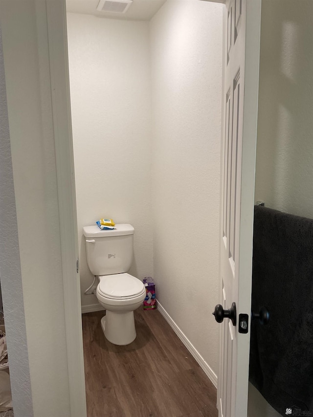 bathroom with baseboards, wood finished floors, and toilet