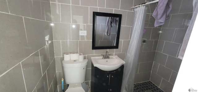 bathroom with tile walls, vanity, toilet, and tiled shower