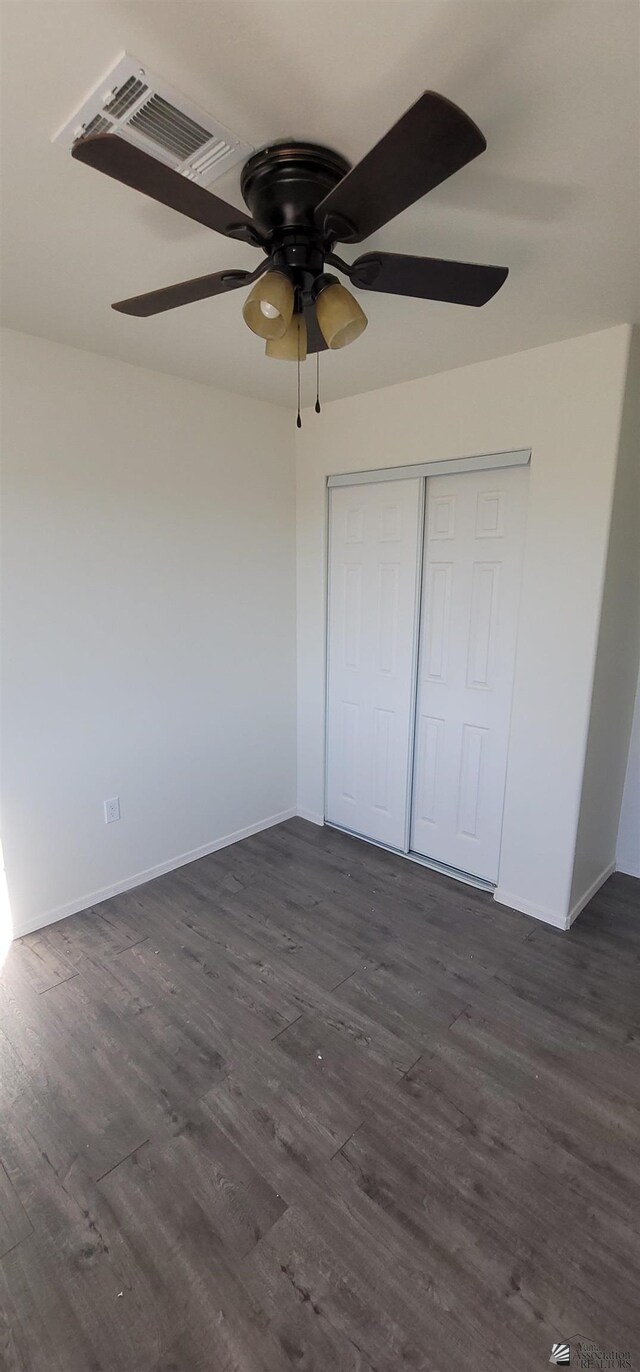 unfurnished bedroom with baseboards, dark wood-style floors, and visible vents