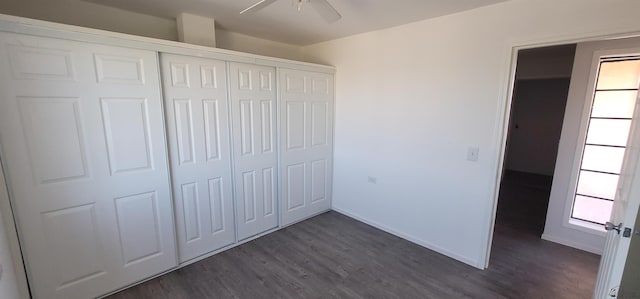 unfurnished bedroom featuring dark wood-style flooring, baseboards, a ceiling fan, and a closet